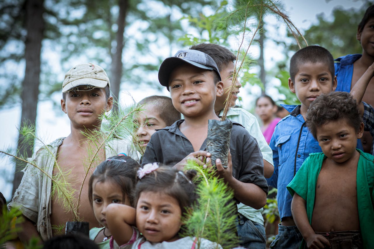 Group of smiling children in Guatemala planting trees together.